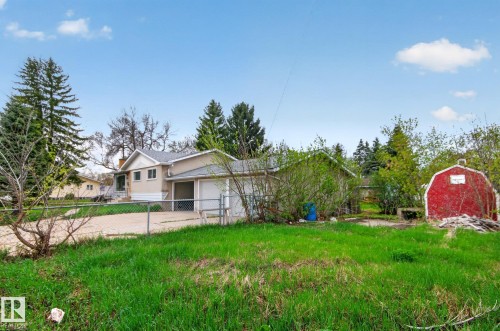Exterior featuring a light-colored siding, attached garage, and a chain-link fence - 11901 42 Street, Edmonton, AB - Outdoor