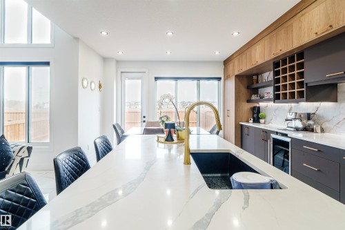 Expansive kitchen island with a gold-finish faucet and integrated sink - 219 28 Street, Edmonton, AB - Indoor Photo Showing Kitchen With Upgraded Kitchen