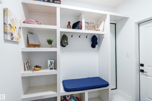 Built-in mudroom storage featuring white cabinetry, multiple open shelves, integrated coat hooks, and a bench - 219 28 Street, Edmonton, AB - Indoor Photo Showing Other Room