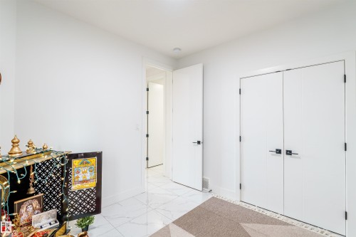 White-painted interior with modern baseboards, white marble-look tile flooring, and matte black door hardware - 219 28 Street, Edmonton, AB - Indoor Photo Showing Other Room