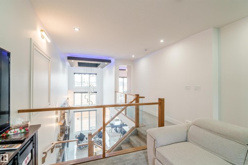 Multi-level interior featuring a wood and glass railing system, recessed ceiling lighting, and a prominent modern chandelier - 219 28 Street, Edmonton, AB - Indoor Photo Showing Other Room