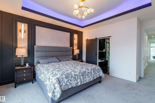 Recessed ceiling with perimeter lighting, a contemporary chandelier, and wainscoting paneling with integrated sconces - 219 28 Street, Edmonton, AB - Indoor Photo Showing Bedroom