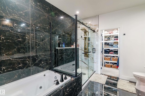Black marbled tile walls and flooring define this bathroom, featuring a jetted tub with black fixtures - 219 28 Street, Edmonton, AB - Indoor Photo Showing Bathroom
