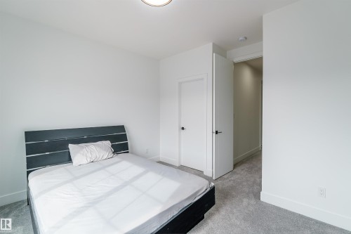 Bedroom featuring neutral gray carpet, white walls, and a contemporary flush-mount ceiling light - 219 28 Street, Edmonton, AB - Indoor Photo Showing Bedroom