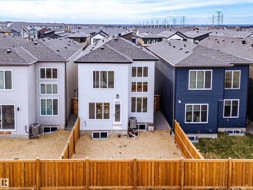 Newly constructed rear elevation featuring light gray siding, a private rear door, multiple large windows, and an unfinished yard - 219 28 Street, Edmonton, AB - Outdoor