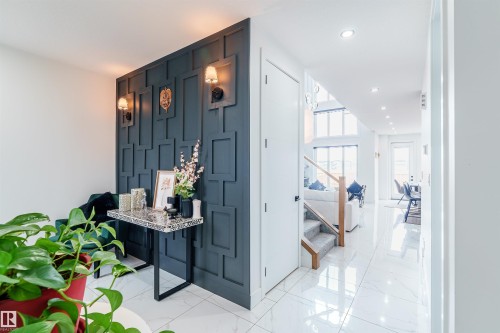 Entryway featuring a striking dark paneled accent wall with sconce lighting, white tile flooring, recessed lighting, and a staircase with a wood handrail - 219 28 Street, Edmonton, AB - Indoor Photo Showing Other Room