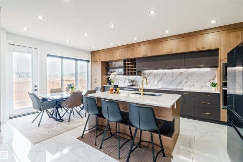 Modern kitchen featuring a large central island with seating, a gold-finish faucet, and integrated appliances - 219 28 Street, Edmonton, AB - Indoor