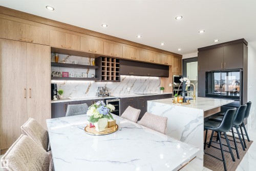 Open-concept kitchen featuring marble-finish countertops, wood-finish cabinetry, a built-in wine rack, a stainless steel beverage cooler, and recessed lighting - 219 28 Street, Edmonton, AB - Indoor Photo Showing Dining Room