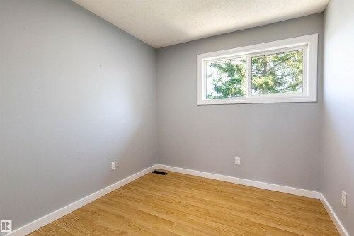Rectangular window with white trim, light gray walls, wood-finish flooring, and white baseboards - 547 Dunluce Road, Edmonton, AB - Indoor Photo Showing Other Room