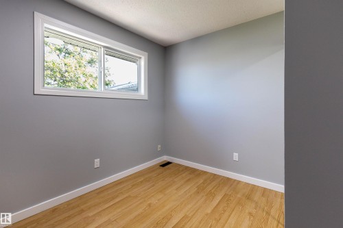 Bright room featuring wood-finish flooring, light grey walls, and white trim - 547 Dunluce Road, Edmonton, AB - Indoor Photo Showing Other Room