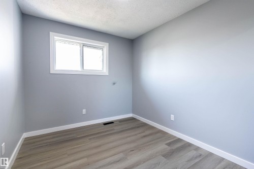 Room featuring neutral gray walls, a white-framed window, textured ceiling, light wood-finish flooring, and white baseboards - 547 Dunluce Road, Edmonton, AB - Indoor Photo Showing Other Room