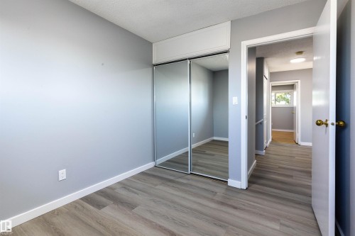 Interior space featuring wood-finish flooring, light gray wall paint, and mirrored sliding closet doors - 547 Dunluce Road, Edmonton, AB - Indoor Photo Showing Other Room