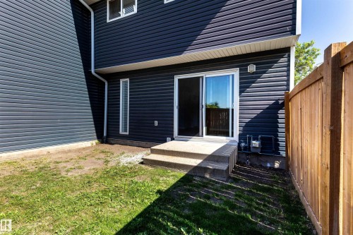 Rear exterior featuring dark horizontal siding, a concrete patio with steps, and a sliding glass door - 547 Dunluce Road, Edmonton, AB - Outdoor With Exterior