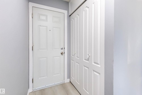 Entryway featuring a paneled door with brushed nickel hardware, light-toned wood-finish flooring, and a multi-panel bifold closet door - 547 Dunluce Road, Edmonton, AB - Indoor Photo Showing Other Room