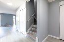 Entryway featuring wood-finish flooring, a contemporary ceiling light fixture, a staircase with a light-toned handrail, and white bi-fold closet doors - 547 Dunluce Road, Edmonton, AB  - Indoor Photo Showing Other Room 