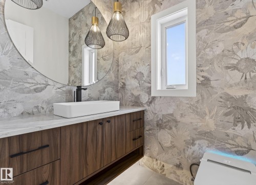 Contemporary vanity featuring wood-finish cabinetry, a stone-finish countertop, and a rectangular vessel sink with a matte black faucet - 5820 110 Street, Edmonton, AB - Indoor Photo Showing Bathroom