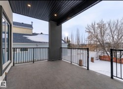 Covered outdoor patio featuring a textured concrete surface, black metal railings, and integrated overhead lighting - 