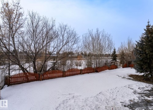 Expansive yard featuring a red picket fence, mature trees, and evergreen landscaping - 5820 110 Street, Edmonton, AB - Outdoor