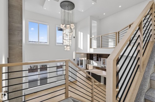 Modern open-concept interior featuring light wood-finish flooring, a two-story ceiling, and multiple large windows - 5820 110 Street, Edmonton, AB - Indoor Photo Showing Other Room