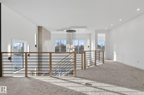 Upper-level landing featuring a contemporary chandelier, recessed lighting, and a horizontal bar railing with wood newel posts - 5820 110 Street, Edmonton, AB - Indoor Photo Showing Other Room