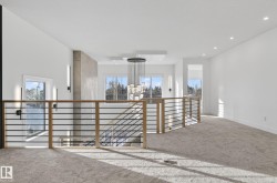 Upper-level landing featuring a contemporary chandelier, recessed lighting, and a horizontal bar railing with wood newel posts - 