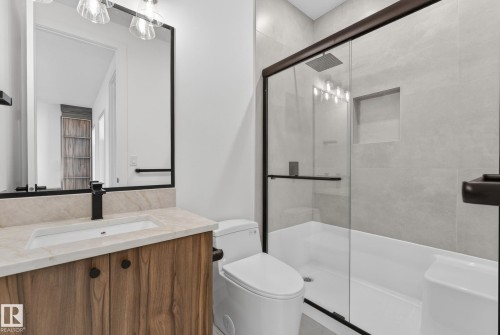 Modern bathroom featuring a wood-finish vanity with a light-toned countertop and an integrated sink - 5820 110 Street, Edmonton, AB - Indoor Photo Showing Bathroom