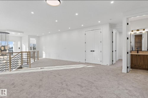 Spacious upper-level landing featuring light gray carpeting, recessed lighting, and a contemporary chandelier - 5820 110 Street, Edmonton, AB - Indoor Photo Showing Other Room