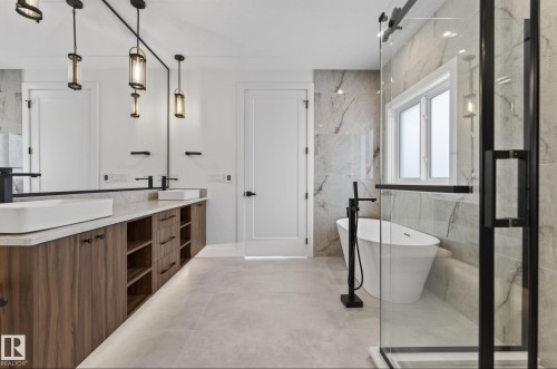 Modern bathroom featuring a freestanding soaking tub with a floor-mounted faucet, a glass-enclosed shower with black trim, and a dual vanity with wood-finish cabinetry, countertop lighting, and vessel sinks - 5820 110 Street, Edmonton, AB - Indoor