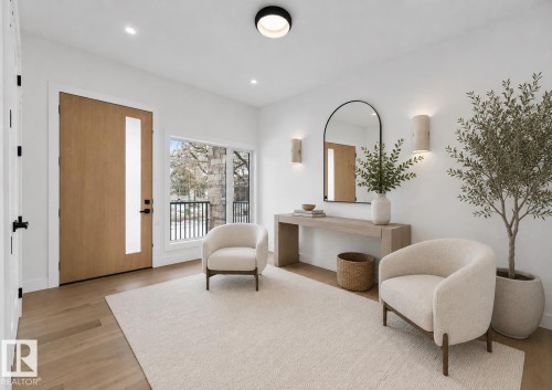 Entryway featuring light wood-finish flooring, a contemporary wood door with a vertical frosted glass pane, and a large window providing exterior views - 5820 110 Street, Edmonton, AB - Indoor