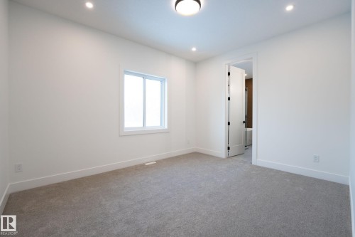 Carpeted room featuring white walls, bright window, recessed lighting, and a white interior door with black hardware - 5820 110 Street, Edmonton, AB - Indoor Photo Showing Other Room