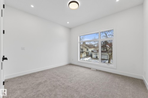 Spacious room featuring a large multi-pane window, recessed lighting, a modern flush-mount ceiling fixture, plush gray carpeting, and crisp white trim - 5820 110 Street, Edmonton, AB - Indoor Photo Showing Other Room