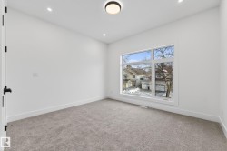 Spacious room featuring a large multi-pane window, recessed lighting, a modern flush-mount ceiling fixture, plush gray carpeting, and crisp white trim - 