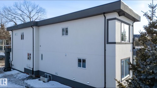 Contemporary exterior with light-colored stucco siding, dark trim accents, and a dark flat roofline - 5820 110 Street, Edmonton, AB - Outdoor With Exterior