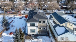 Contemporary two-story exterior featuring white siding with dark trim, multiple large windows, a second-story balcony with dark railings, and a dark shingle roof - 
