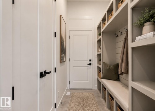 Built-in mudroom organization system featuring open shelving, integrated bench seating, storage cubbies, and coat hooks - 5820 110 Street, Edmonton, AB - Indoor Photo Showing Other Room