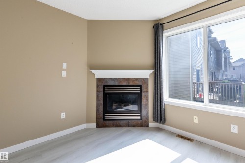 Corner fireplace featuring a tile surround and white mantel - #116 5001 62 St, Beaumont, AB - Indoor Photo Showing Other Room With Fireplace