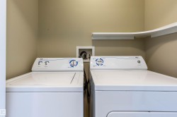 Dedicated laundry area featuring a white top-load washing machine, a white front-load dryer, and a built-in corner shelf for organization - 