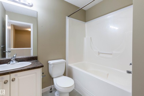 Bathroom featuring a white vanity with a dark countertop, an integrated sink, and a chrome faucet - #116 5001 62 St, Beaumont, AB - Indoor Photo Showing Bathroom