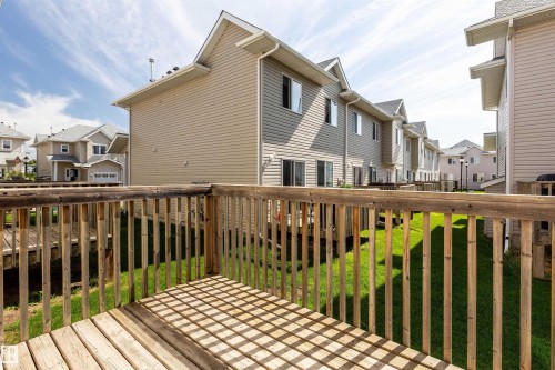 Wooden deck with baluster railings and a view of a grassy yard - #116 5001 62 St, Beaumont, AB - Outdoor With Deck Patio Veranda With Exterior