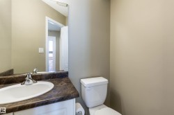 Powder room featuring a white pedestal sink, dark countertop, and chrome faucet - 