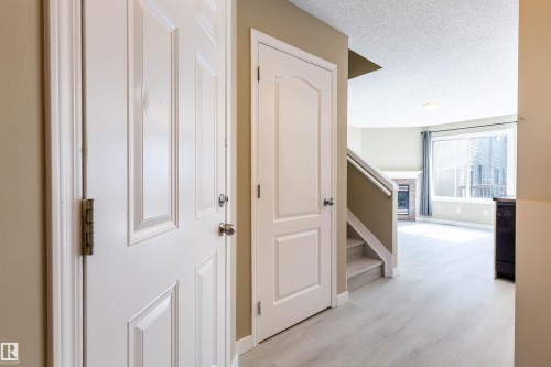 Entryway with light wood-finish flooring, white paneled doors, and neutral wall tones - #116 5001 62 St, Beaumont, AB - Indoor Photo Showing Other Room