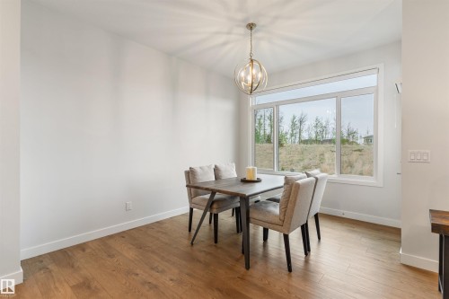 Dining area with wood-finish flooring and a contemporary spherical chandelier - 6003 Edmonds Place Nw, Edmonton, AB - Indoor Photo Showing Dining Room