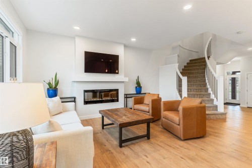 Living area featuring wood-finish flooring, a contemporary fireplace with a mantel, and recessed lighting - 6003 Edmonds Place Nw, Edmonton, AB - Indoor Photo Showing Living Room With Fireplace