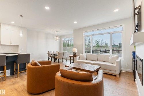 Open-concept living area featuring wood-finish flooring, recessed lighting, and a prominent window - 6003 Edmonds Place Nw, Edmonton, AB - Indoor Photo Showing Living Room