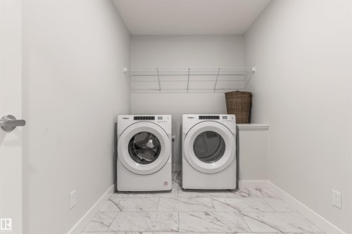 Dedicated laundry area featuring a front-loading washer and dryer set, wire shelving, and a tiled floor - 6003 Edmonds Place Nw, Edmonton, AB - Indoor Photo Showing Laundry Room