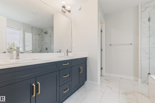 Bathroom featuring a double vanity with dark cabinetry, brass hardware, and a white countertop - 6003 Edmonds Place Nw, Edmonton, AB - Indoor Photo Showing Bathroom