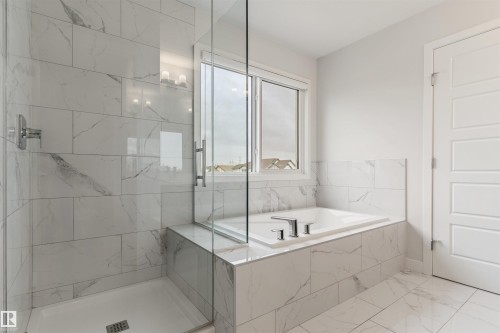Spacious bathroom featuring a glass-enclosed shower with a built-in bench, a built-in soaking tub with chrome fixtures, and large-format tile flooring - 6003 Edmonds Place Nw, Edmonton, AB - Indoor Photo Showing Bathroom