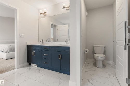 Bathroom with a dual vanity featuring dark blue cabinetry and a white countertop - 6003 Edmonds Place Nw, Edmonton, AB - Indoor Photo Showing Bathroom