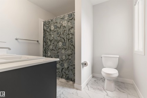 Bathroom featuring a vanity with an integrated double sink, white countertop, and contemporary faucets - 6003 Edmonds Place Nw, Edmonton, AB - Indoor Photo Showing Bathroom