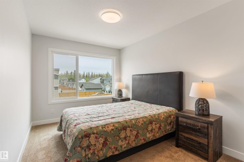 Bright bedroom featuring a large window, neutral wall paint, and light brown carpeting - 6003 Edmonds Place Nw, Edmonton, AB - Indoor Photo Showing Bedroom